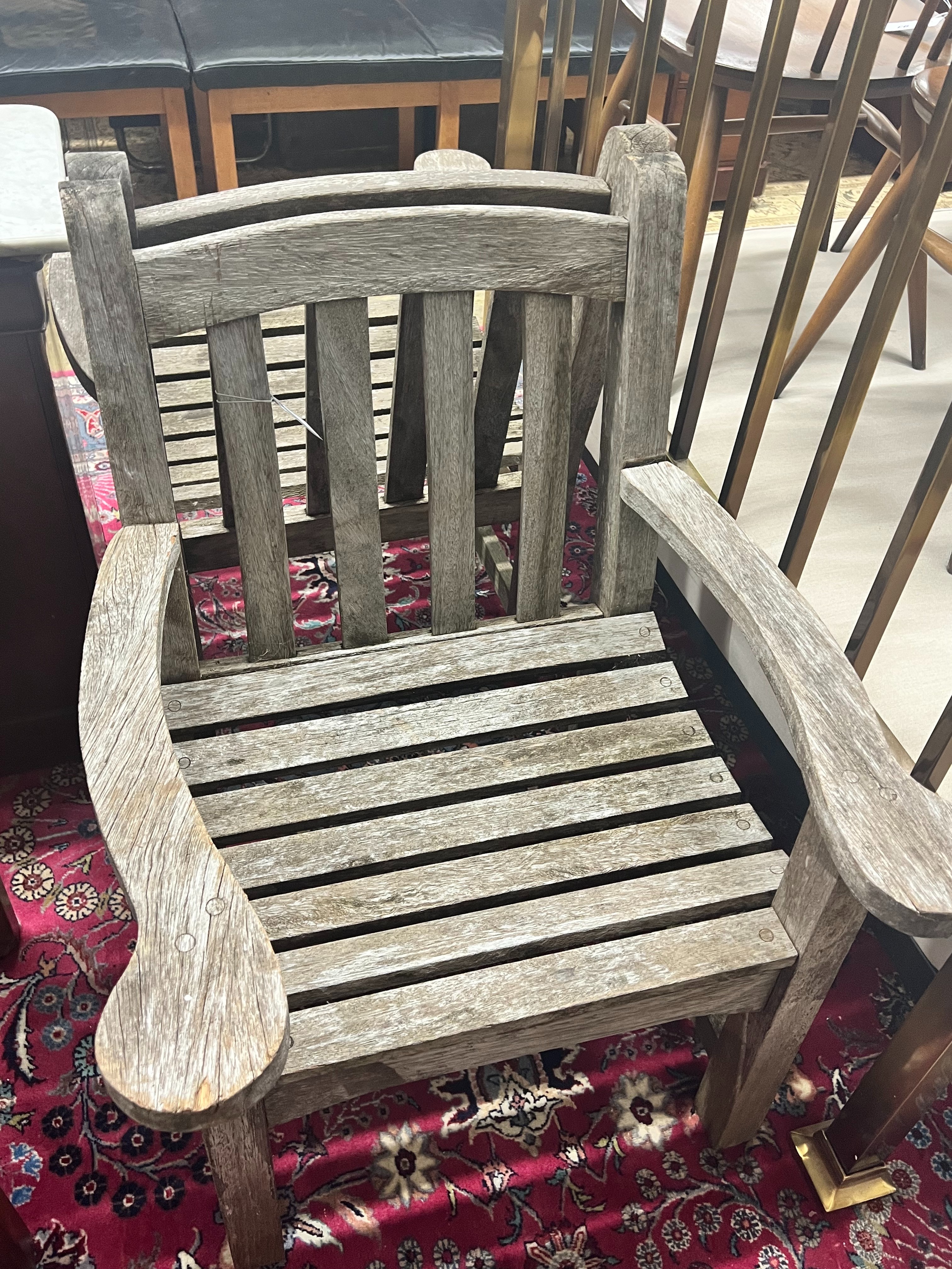 A pair of weathered teak slatted garden elbow chairs, width 64cm depth 60cm height 86cm